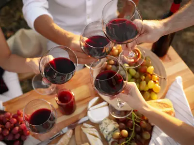 Friends holding glasses of wine at table, closeup