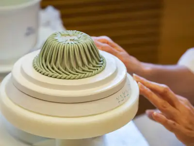 A porcelain maker demonstrates how to make her porcelain goods at her work station.