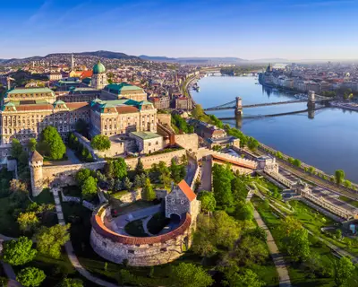 Budapest, Hungary - Aerial panoramic skyline view of Buda Castle Royal Palace with Szechenyi Chain Bridge, Hungarian Parliament and Matthias Church at sunrise with clear blue sky
