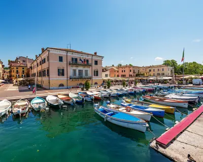 Small old port of the village of Bardolino with many boats moored. Tourist resort on the coast of Lake Garda (Lago di Garda). Verona province, Veneto, Italy, southern Europe.