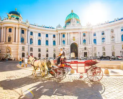 Vienna, Austria - 19 June, 2022: Hofburg Palace and horse carriage on sunny Wien street