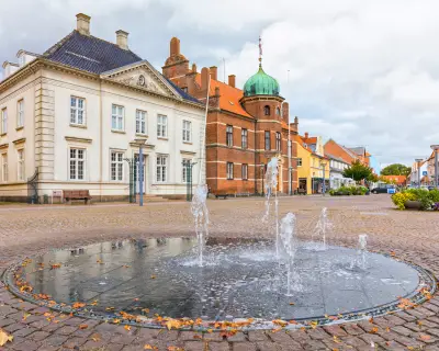 Town square at Stege on Danish island of Møn with fountain, town hall and historic savings bank