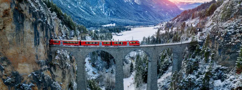 Aerial view of Train passing through famous mountain in Filisur, Switzerland. Landwasser Viaduct world heritage with train express in Swiss Alps snow winter scenery.