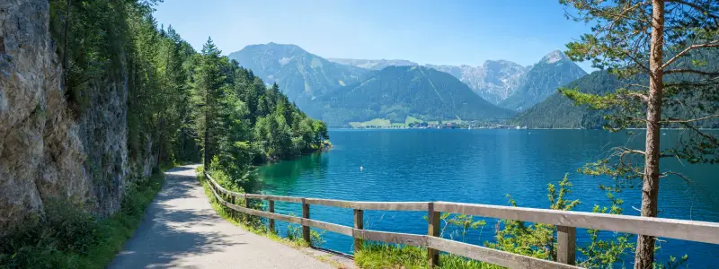 walkway and bike route along lake achensee east side in idyllic mountain landscape. tirolean alps in summer